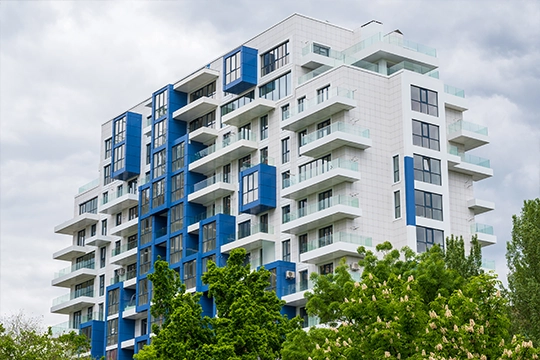 nowoczesny-niebieski-blok nowoczesny, wielopiętrowy apartamentowiec o unikalnym, modułowym designie, zlokalizowany pod zachmurzonym niebem.